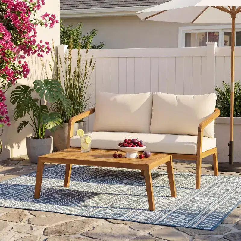 Ensemble Nolan pour terrasse de Christopher Knight Home, composé d’un canapé 2 places et d’une table basse en bois d’acacia et résine tressée, avec coussins